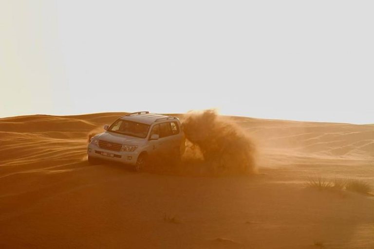 A photo of a 4x4 travelling across sand dunes.