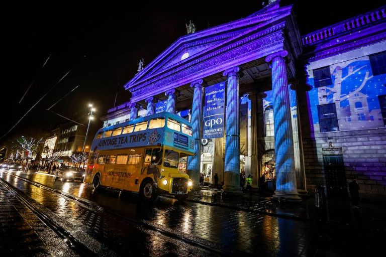 A photo of a Dublin tea bus driving past An Post.